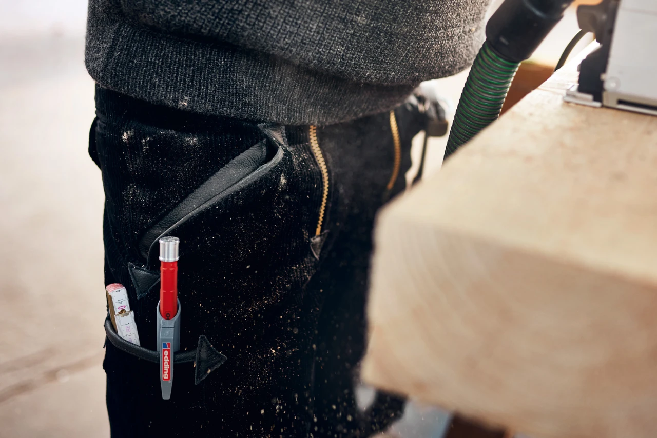 Eine Person die eine Handwerkerhose trägt, wird seitlich fotografiert. In der Seitentasche der Hose ist ein Edding eingehängt